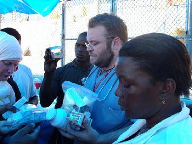 Remitting medical supplies to Dr. Rick a volunteer from "Heat to Heart" at the Haitian soccer stadium turned into a makeshift hospital